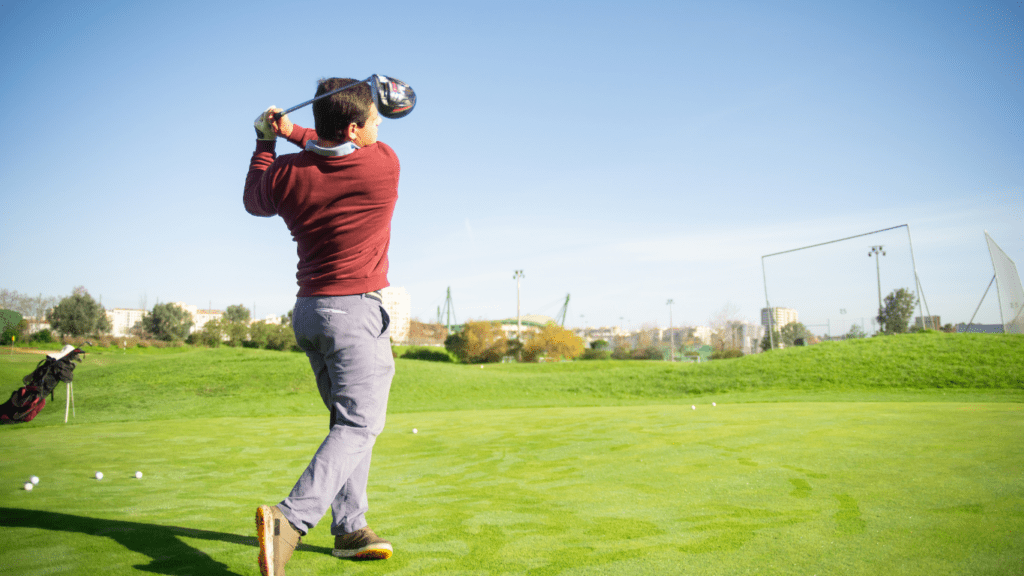 a person is swinging a golf club on a green field