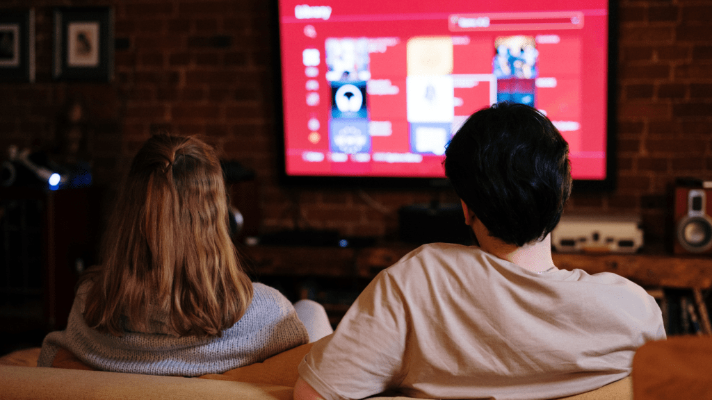 two people sitting on a couch watching tv