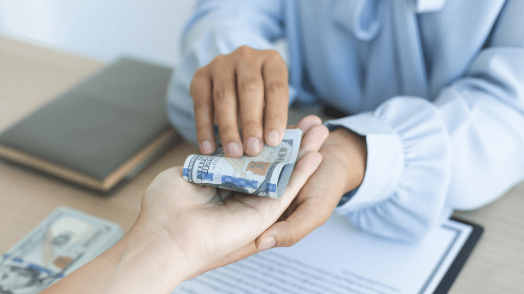 a person handing money to another person at a desk