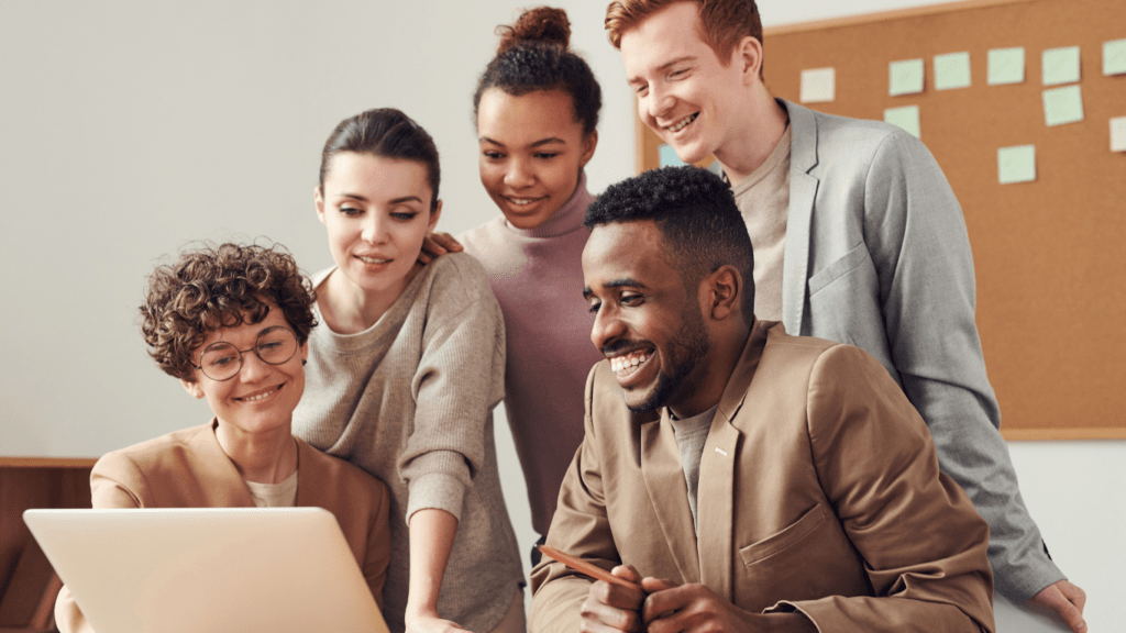 a group of people sitting around a table with a laptop