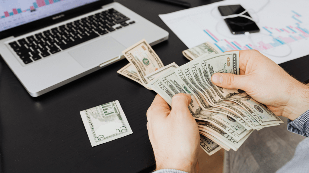 a person is holding two stacks of cash in their hands