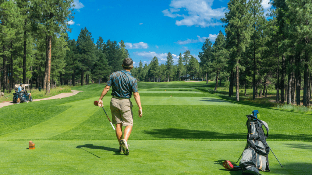 a person is swinging a golf club on a green field