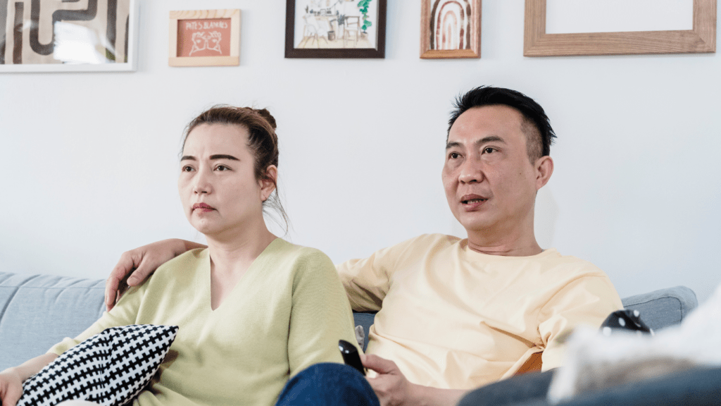 two people sitting on a couch watching tv